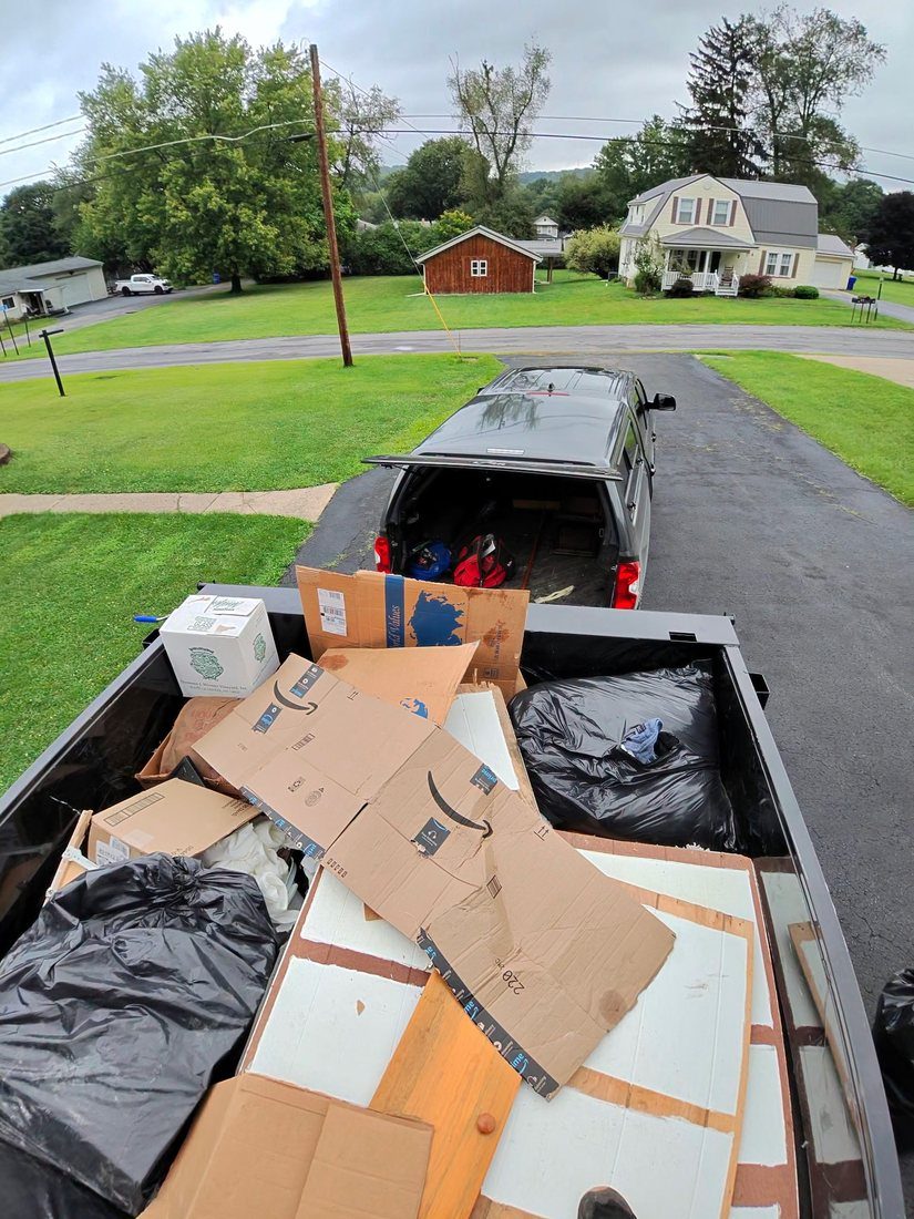 A truck bed loaded with cardboard, packaging and household debris.