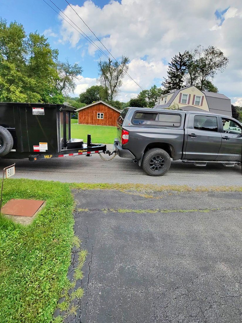 The Iron Valor truck and dump trailer parked on a residential driveway.